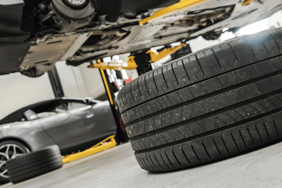 リフトに上げた車両とタイヤが並ぶ整備工場